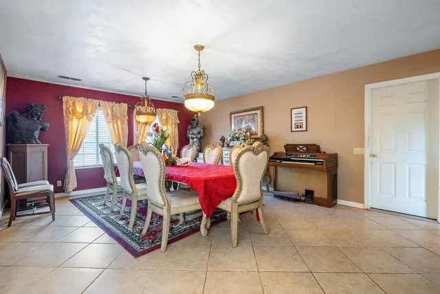a spacious bedroom with a bed a standing fan and a bookshelf
