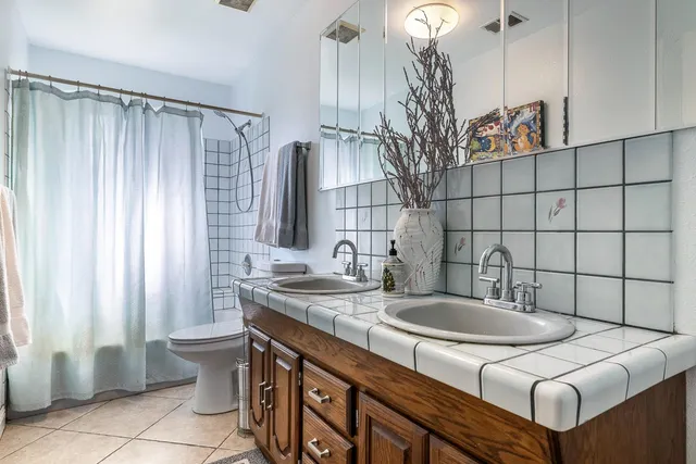 a bathroom with a granite countertop sink a toilet and with mirror
