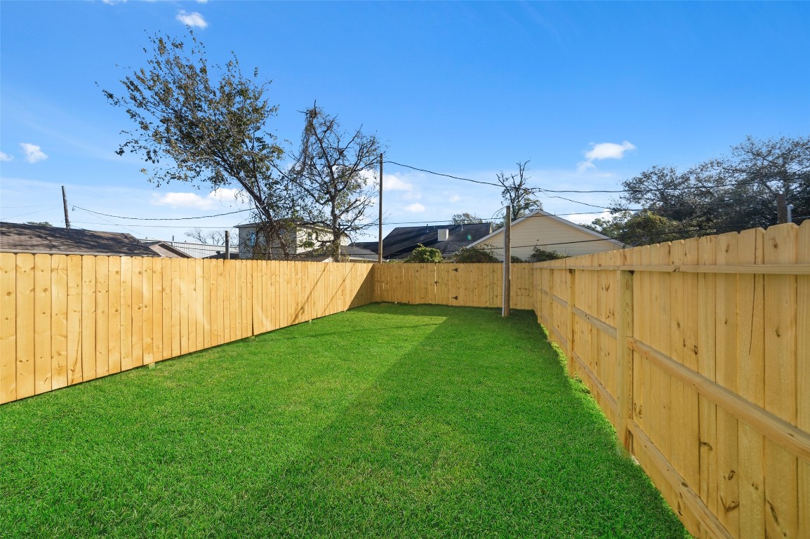 3422 Elser Street Houston, TX 77009 - Photo 2 of 26 A spacious backyard with lush green grass, enclosed by a wooden privacy fence, perfect for outdoor activities and gardening.
