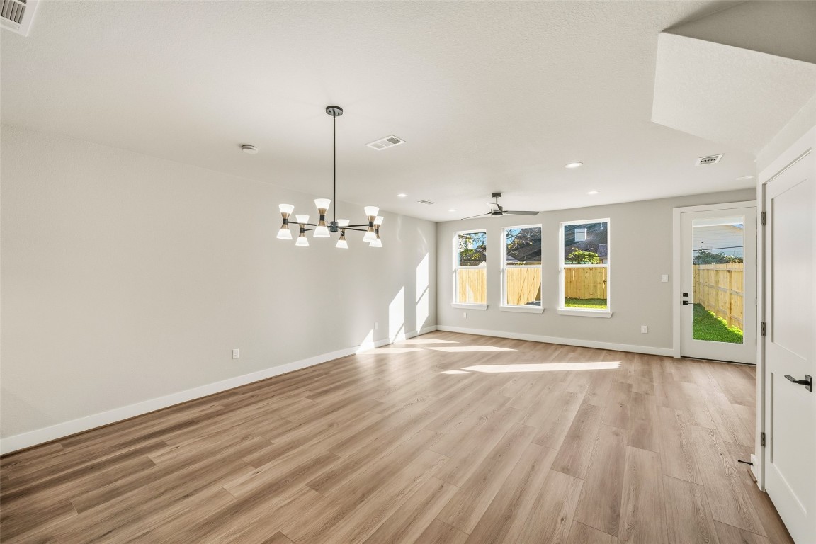 3422 Elser Street Houston, TX 77009 - Photo 4 of 26 This spacious living area features modern wood flooring, neutral walls, and large windows that provide ample natural light. A stylish chandelier and ceiling fan enhance the room, while a door leads to a fenced backyard, perfect for indoor-outdoor living.