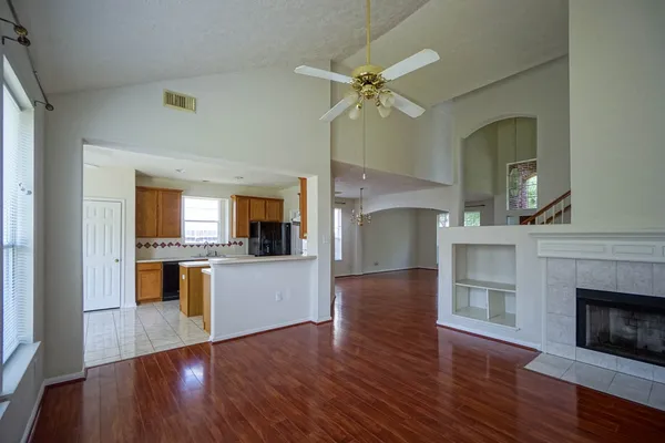 a living room with stainless steel appliances kitchen island a fireplace and wooden floor