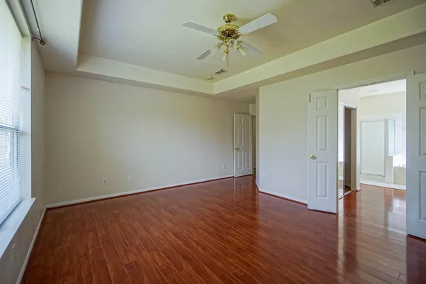 a view of an empty room with a window and wooden floor