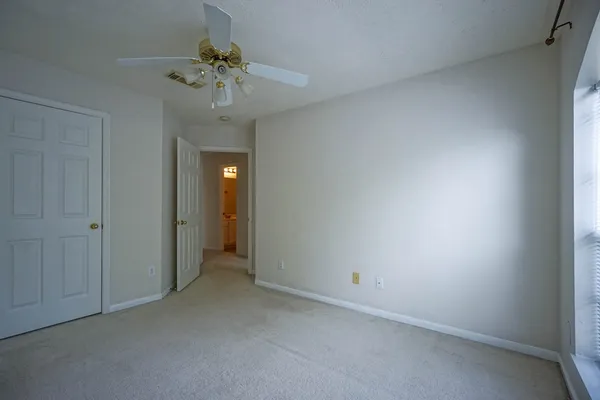 a view of an empty room and a chandelier fan