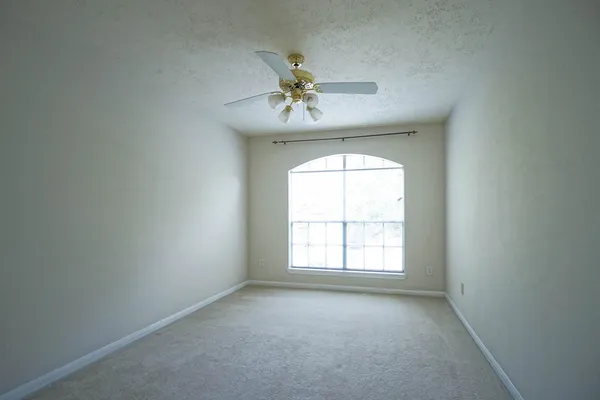 an empty room with windows and chandelier fan
