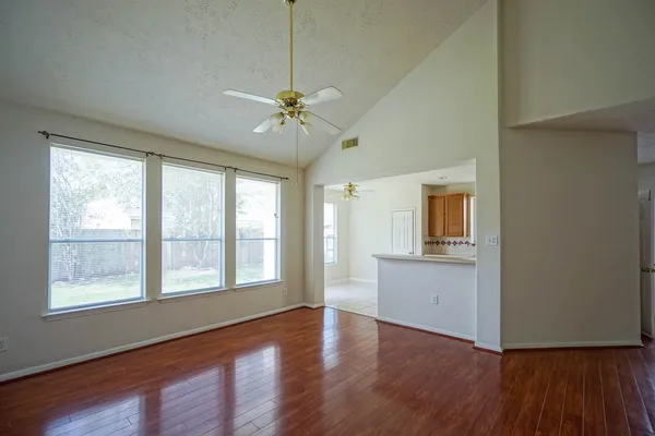 a view of an empty room with a window and wooden floor