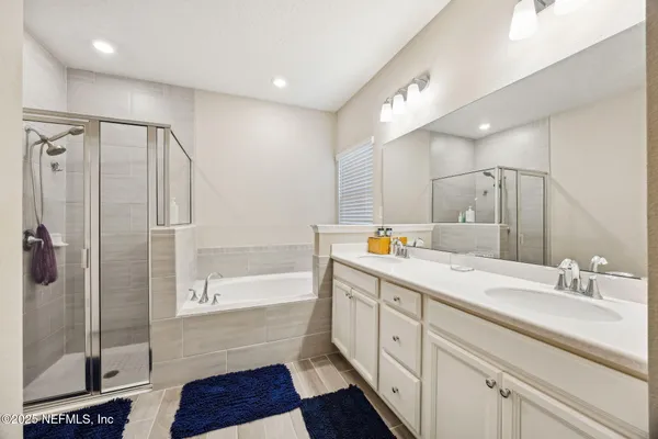 a spacious bathroom with a double vanity sink a large mirror and shower