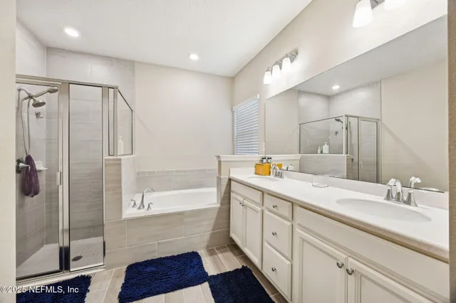 a spacious bathroom with a double vanity sink a large mirror and shower