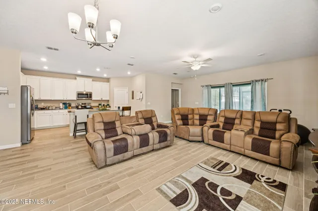 a living room with furniture kitchen view and a chandelier