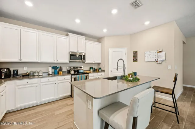 a kitchen with granite countertop white cabinets and stainless steel appliances