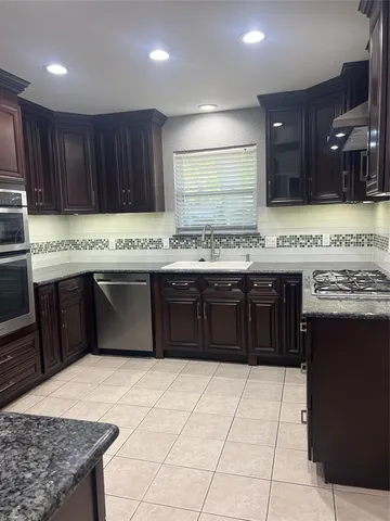 a kitchen with a stove a sink a refrigerator and a oven