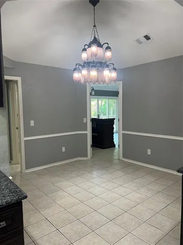 a view of an empty room with a chandelier fan and fire place