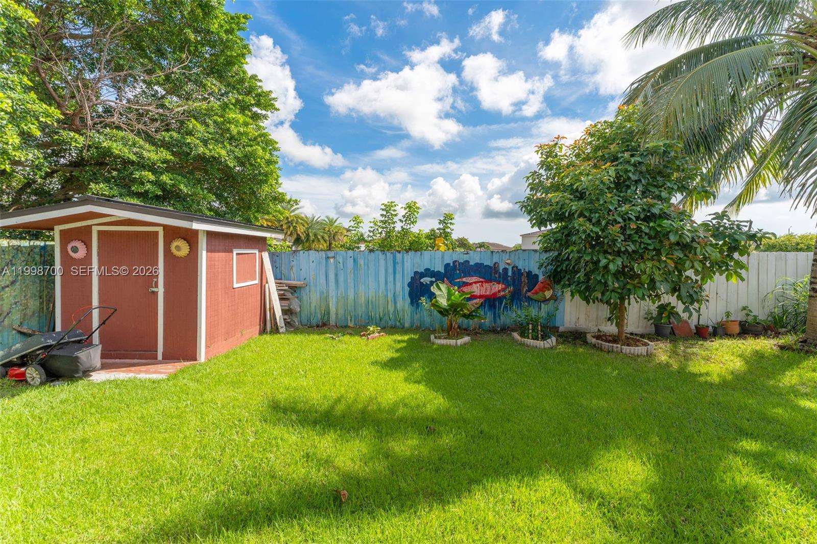 13471 Southwest 278th Terrace Homestead, FL 33032 - Photo 13 of 32 a view of a backyard with plants and a large tree