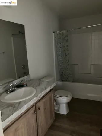 a bathroom with a granite countertop sink a toilet a mirror and shower