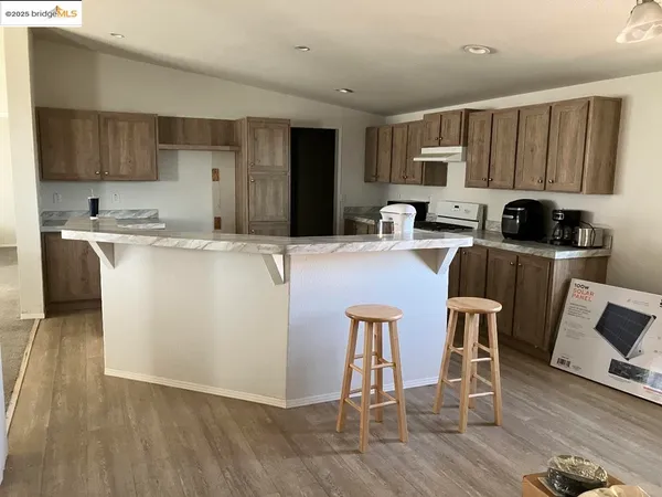 a kitchen with kitchen island granite countertop a stove top oven a sink dishwasher a dining table and chairs with wooden floor