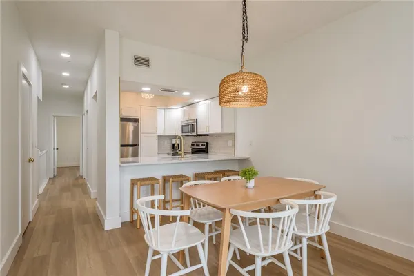 a kitchen with stainless steel appliances kitchen island granite countertop a dining table chairs and a refrigerator