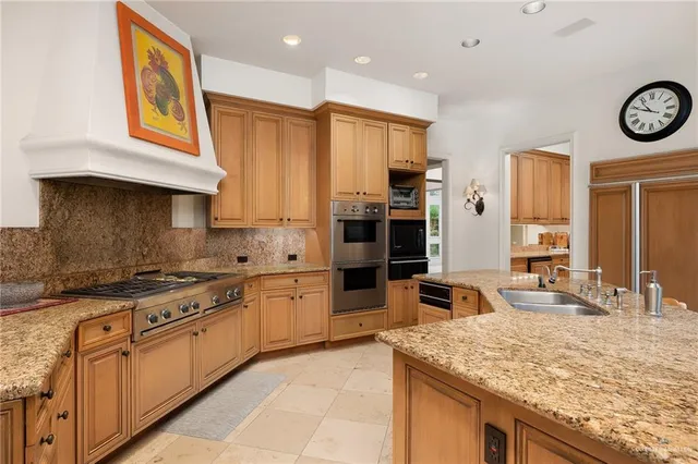 a kitchen with stainless steel appliances granite countertop a stove top oven a sink a dining table and chairs
