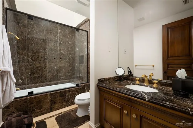 a bathroom with a granite countertop sink toilet and shower