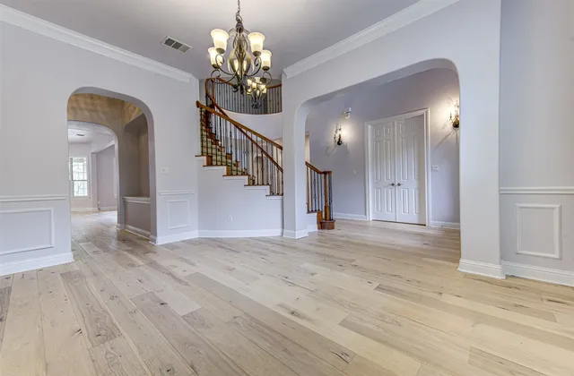 a view of a hallway with wooden floor and chandelier