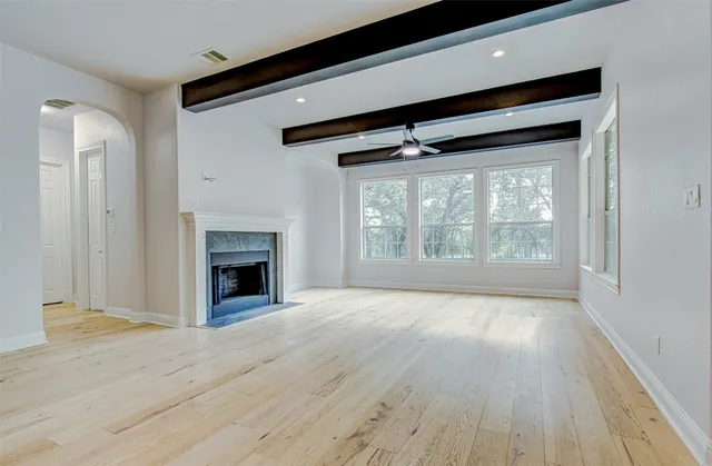 an empty room with wooden floor fireplace and windows