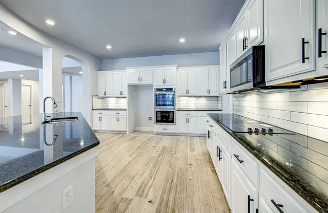 a kitchen with kitchen island white cabinets and stainless steel appliances