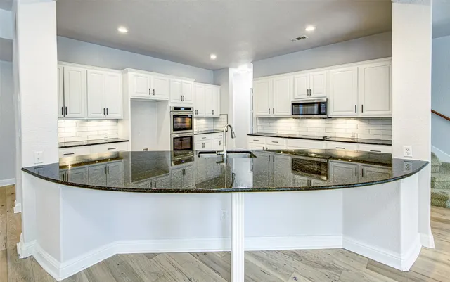 a kitchen with stainless steel appliances granite countertop a sink a stove and a refrigerator