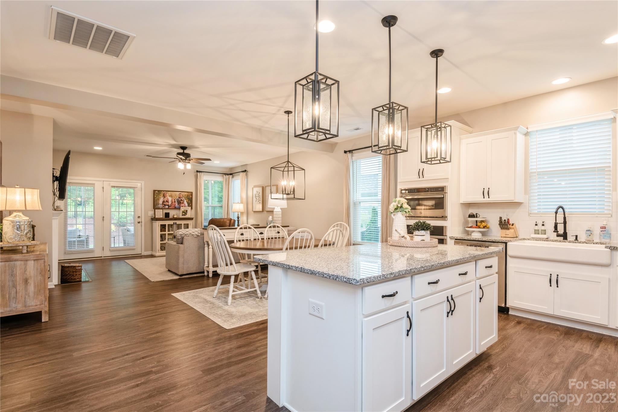 3028 Eagle Ridge Lane Indian Trail, NC 28079 - Photo 8 of 38 a kitchen with stainless steel appliances kitchen island a refrigerator a sink dishwasher a oven and a dining table with wooden floor
