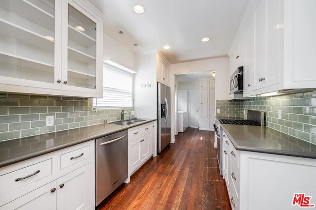 a kitchen with granite countertop a sink a counter space stainless steel appliances and cabinets