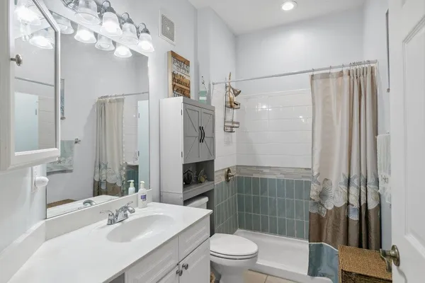 a bathroom with a sink a toilet a mirror and shower