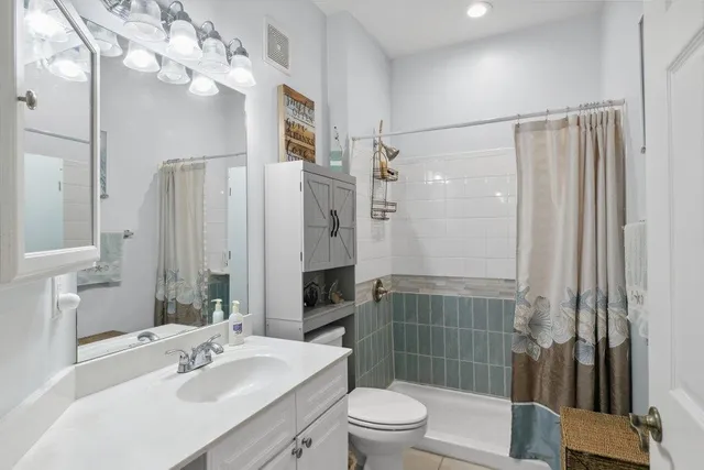 a bathroom with a sink a toilet a mirror and shower