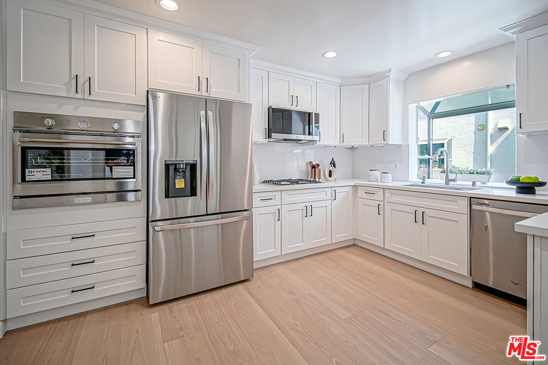 2950 South Bentley Avenue, Unit 3 Los Angeles, CA 90064 - Photo 13 of 32 a kitchen with white cabinets stainless steel appliances and sink