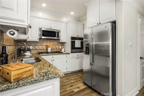 a kitchen with stainless steel appliances kitchen island granite countertop a dining table chairs and a refrigerator