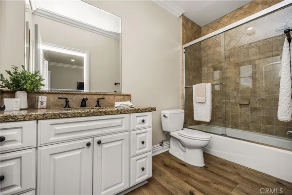 a bathroom with a granite countertop sink a toilet and shower
