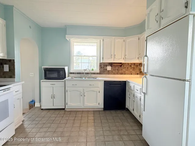 a kitchen with granite countertop a refrigerator sink and microwave