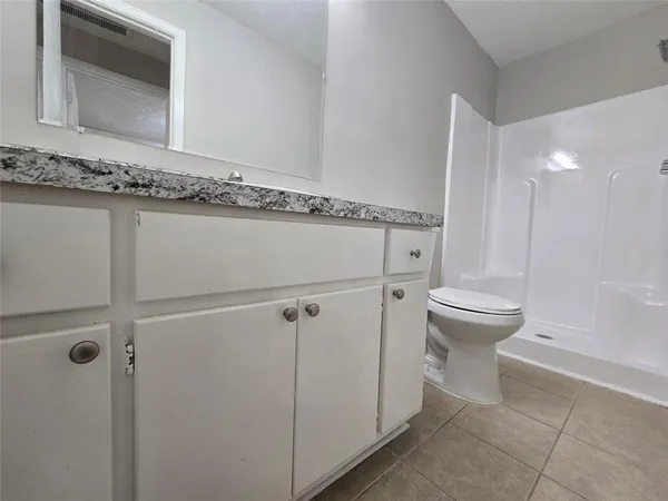 a bathroom with a granite countertop sink mirror vanity and toilet