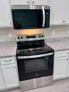 20193 Southwest 83rd Street Dunnellon, FL 34431 - Photo 16 of 31 a kitchen with granite countertop a stove and a microwave