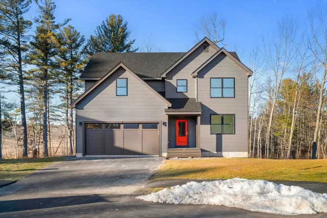 a front view of a house with yard and trees