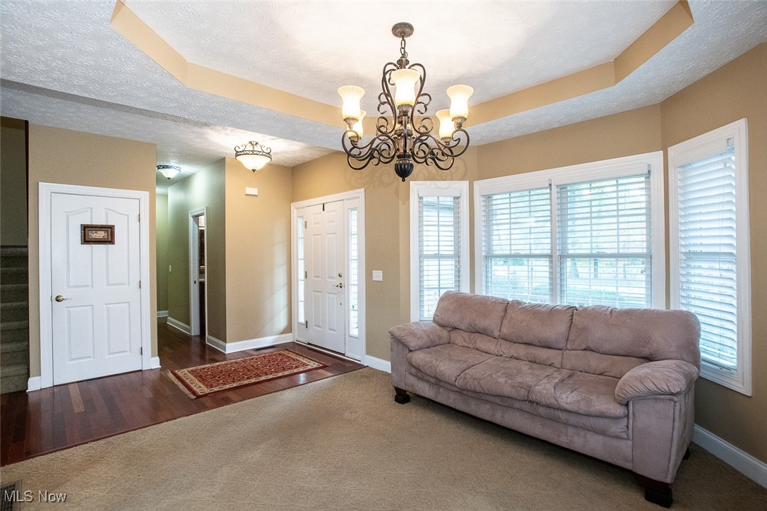 630 Rundle Street Lagrange, OH 44050 - Photo 5 of 49 Living room with a textured ceiling, a raised ceiling, a chandelier, dark carpet, and dark wood-style floors