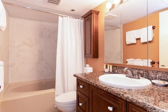 a bathroom with a granite countertop sink toilet and shower