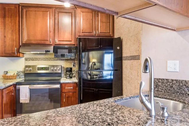 a kitchen with stainless steel appliances kitchen island granite countertop a refrigerator and a stove top oven