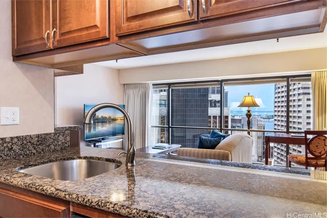 a kitchen sink with granite countertop a stove and cabinets
