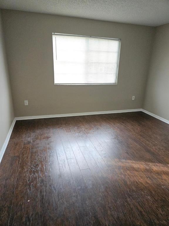 5041 Wiles Road, Unit 201 Coconut Creek, FL 33073 - Photo 13 of 17 an empty room with wooden floor and windows