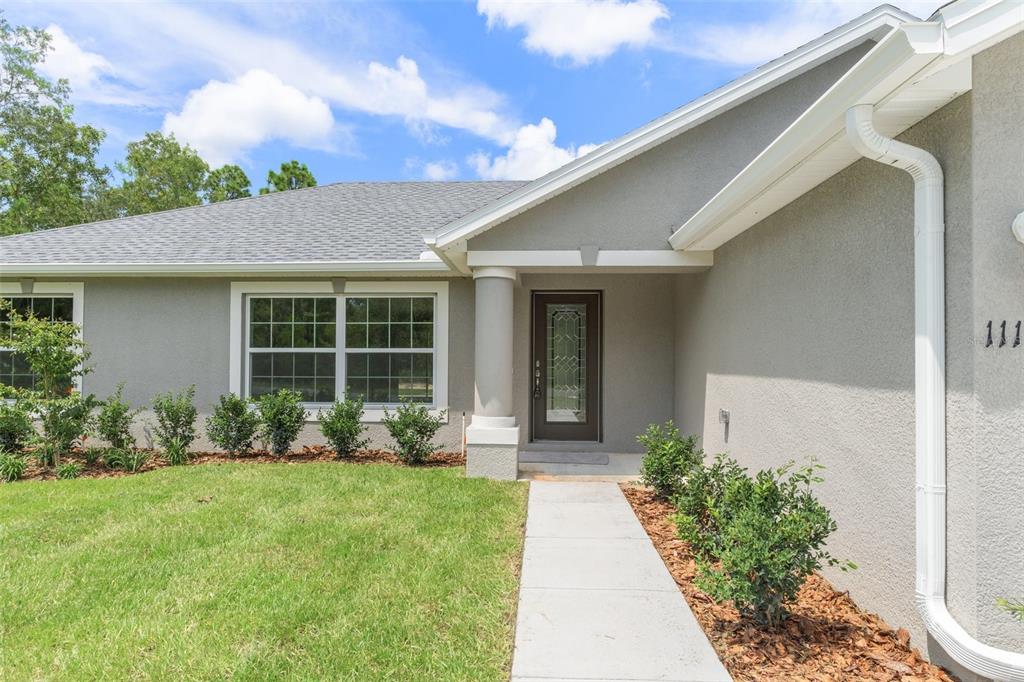 16375 Kakawi Road Brooksville, FL 34614 - Photo 3 of 30 a front view of a house with garden and porch