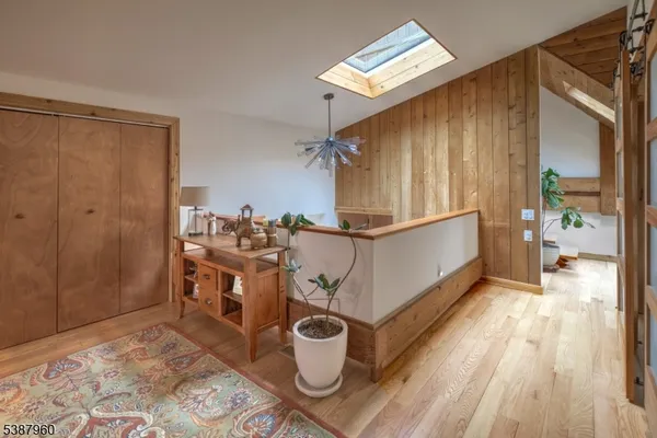 a view of a hallway with wooden floor and a bathroom