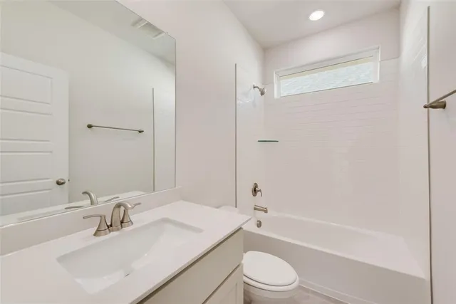 a bathroom with a bathtub shower sink vanity mirror and toilet