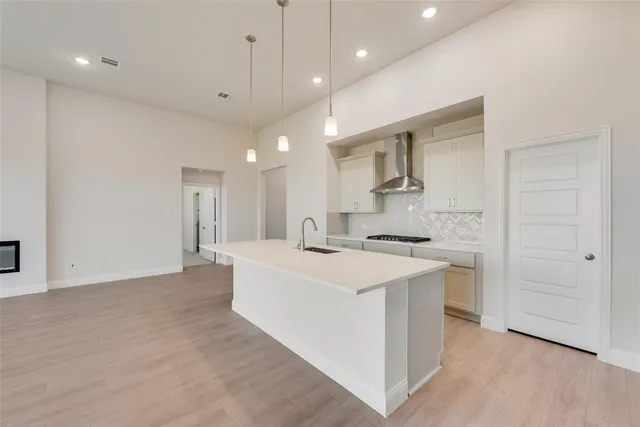 a kitchen with a sink a stove a refrigerator and white cabinets