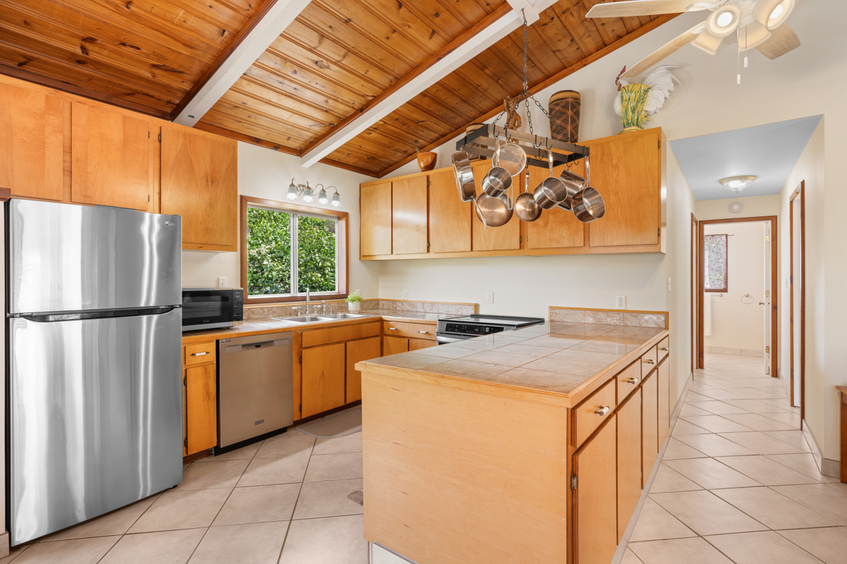 76-6179 Mania Road Kailua-Kona, HI 96740 - Photo 6 of 30 a kitchen with stainless steel appliances granite countertop a refrigerator a sink a stove with wooden cabinets