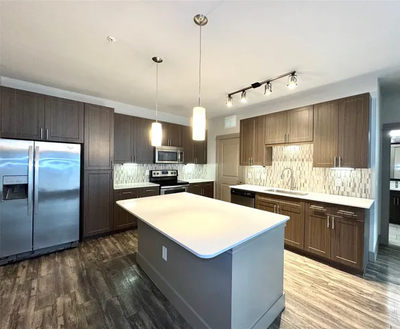a kitchen with kitchen island a sink stainless steel appliances and cabinets