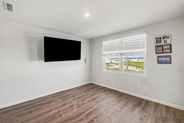 a view of an empty room with wooden floor and windows