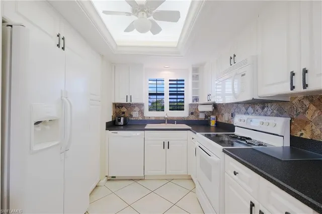 a kitchen with granite countertop white cabinets and white appliances