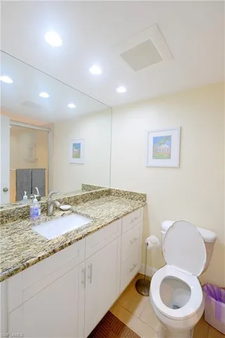 a bathroom with a granite countertop toilet sink and mirror